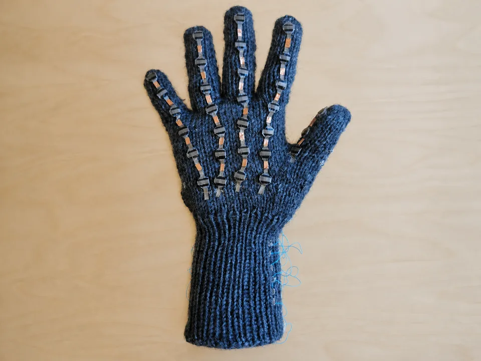 Tactile sensing glove with pressure sensors across the fingers and palm